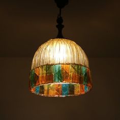 a multicolored glass light hanging from a ceiling fixture in a room with dark walls