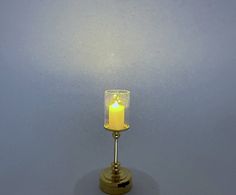 a lit candle is sitting on top of a small stand with a blue wall in the background