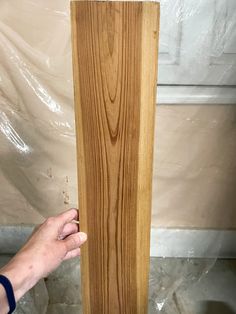 a person holding a piece of wood in their hand next to a wooden flooring board