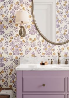 a bathroom vanity with purple drawers and wallpaper