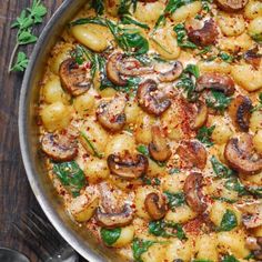 a pan filled with pasta and mushrooms on top of a wooden table