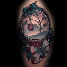 a snow globe tattoo on the arm with holly branches and an ornament in it