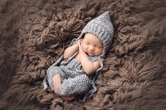 a newborn baby wearing a crochet hat and sleeping on a brown blanket