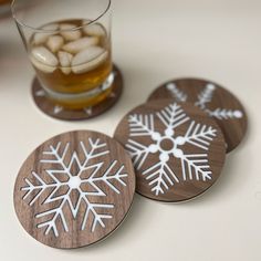 "This is a snowflake coaster set made from wood and acrylic. The set of Christmas coasters includes 4 different snowflakes designs.  Spruce up your holiday decor with this custom snowflake coaster set. These make great hostess gifts, teacher gifts or stocking stuffers. SIZE The coasters are 4\" in diameter. Laser cut from 5/32\" walnut and inlaid with 1/8\" white acrylic. The slight difference in thickness gives the snowflake a little extra dimension. Everything is applied to a base of 1/8\" white acrylic to protect your surfaces. LINKS TO ADDITIONAL COLORS Red Snowflake Coaster Set https://bauergiftsco.etsy.com/listing/1347560973/red-snowflake-coaster-set-christmas Black Snowflake Coaster Set https://bauergiftsco.etsy.com/listing/1347562745/black-snowflake-coaster-set-christmas Green Snow Christmas Coaster Ideas, Christmas Wood Gifts, Wooden Christmas Gift Ideas, Cnc Christmas Decorations, Cnc Gift Ideas, Coasters Christmas, Coasters Wood, Wooden Christmas Coasters, Acrylic Gift