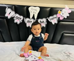 a baby sitting on top of a bed in front of a sign that says toothy to me