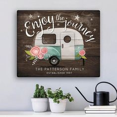 a wooden sign that says enjoy the journey with an old camper and flowers on it