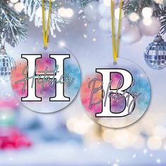 two ornaments hanging from a christmas tree with the letter h and b on them in front of a blurry background