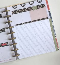 a planner is open on top of a white surface with black and red trimmings