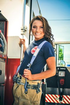 a woman standing in front of a fire truck with her hand on the door handle