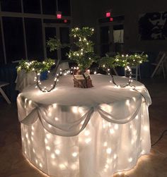 a table with lights on it and some trees in the centerpieces that are lit up