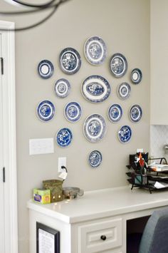 blue and white plates are arranged on the wall above a desk in this home office