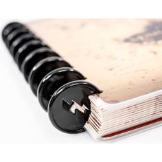 an open spiral bound book with a black button on the front and white pages inside