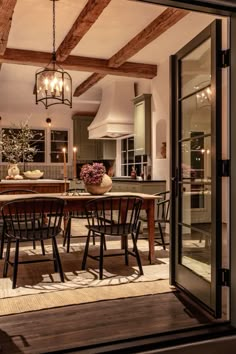 the dining room table is surrounded by black chairs and wooden beams with lights hanging from them