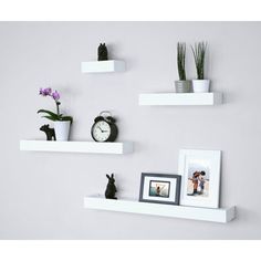 three white floating shelves with pictures and photos on them