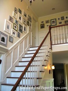 a staircase with pictures on the wall and chandelier