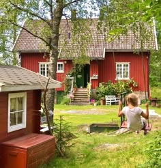 a woman sitting on a bench in front of a red house