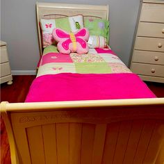 a child's bed with pink and green sheets