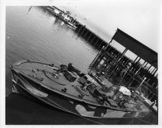 an old photo of a boat tied up to the dock with other boats in the background