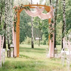 an outdoor wedding ceremony setup with pink drapes and white flowers on the arbors