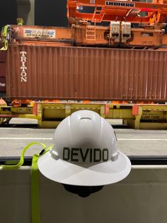 a white hard hat with the word devido written on it sitting in front of a train