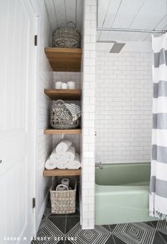 a bathroom with black and white tile flooring and shelving in the shower area