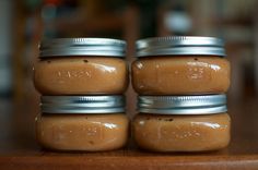 four jars filled with peanut butter sitting on top of a wooden table