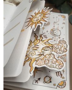 an open notebook with stickers on it and some papers next to it that have designs on them