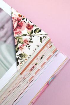 a stack of papers on top of each other next to a pink flowered wall