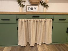 a kitchen with green cabinets and white curtains