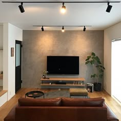 a living room with couches and a flat screen tv mounted on the wall above it