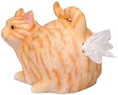 an orange and white cat figurine with tissue paper in its mouth on a white background