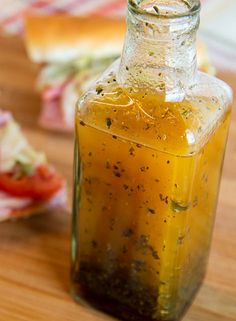 a glass bottle filled with liquid sitting on top of a wooden table next to slices of bread