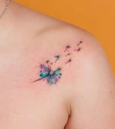 the back of a woman's shoulder with a dandelion tattoo