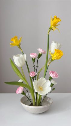 a white bowl filled with flowers on top of a table