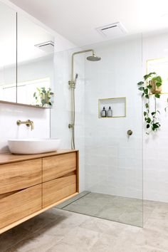 a bathroom with a sink, mirror and shower head in the corner next to a wooden cabinet