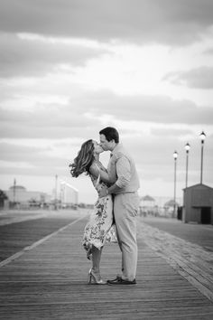 a man and woman kissing on a pier