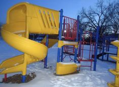 an empty playground in the winter with snow on the ground and children's play equipment