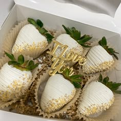 a box filled with white frosted strawberries covered in gold sprinkles