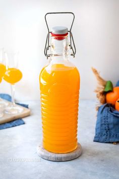 an orange beverage in a glass bottle on a table