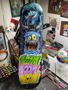 a skateboard covered in graffiti sitting on top of a table next to art supplies