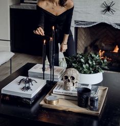 a woman standing in front of a table with books and candles on top of it