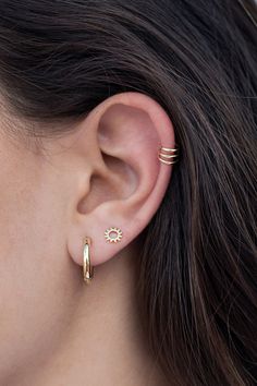 a woman wearing two gold hoop earrings and a small diamond earring in front of her ear