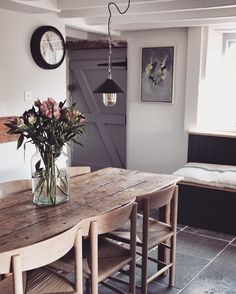 a vase with flowers sitting on top of a wooden table next to a bench in a room