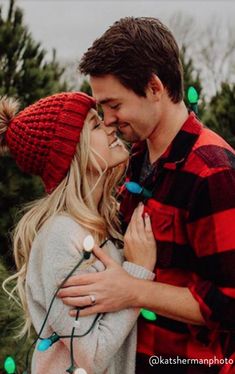 a man and woman standing next to each other in front of christmas trees with lights