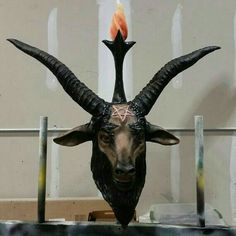 a horned goat head with a burning candle on it's forehead is shown in front of a wall