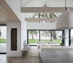 a living room filled with white furniture next to a large glass window covered in trees