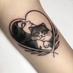 a black and white cat sitting on top of a woman's arm with a heart shaped