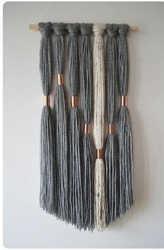 the wall hanging is made out of yarn and wooden dows, with several tassels attached to it