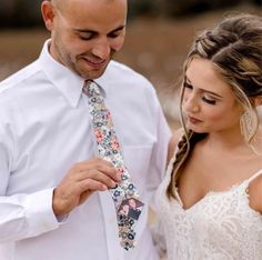 a man and woman standing next to each other with a tie on their necktie