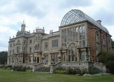 an old building with many windows on the front and side of it, surrounded by lush green grass